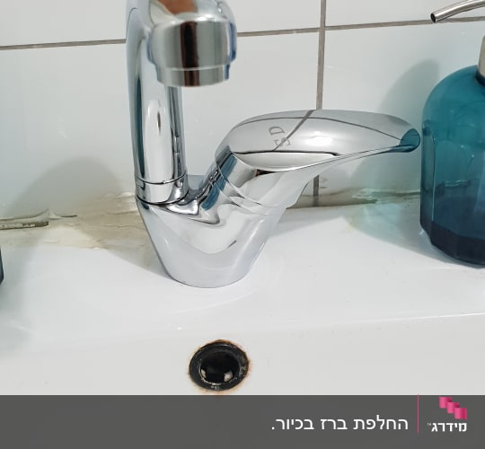 ברז כרום על כיור לבן עם ניקוז